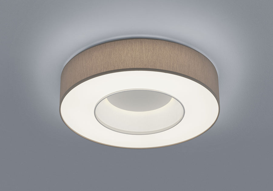 Vue rapprochée du plafonnier cylindrique beige et de son halo lumineux