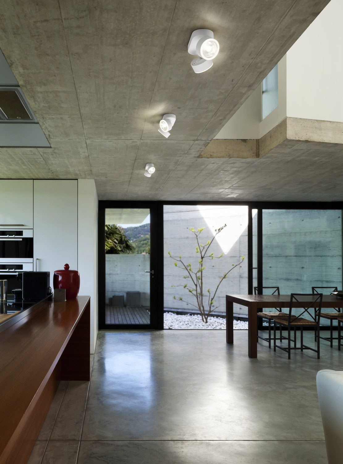 Mise en ambiance dans un intérieur béton, plusieurs plafonniers blancs orientés vers le sol