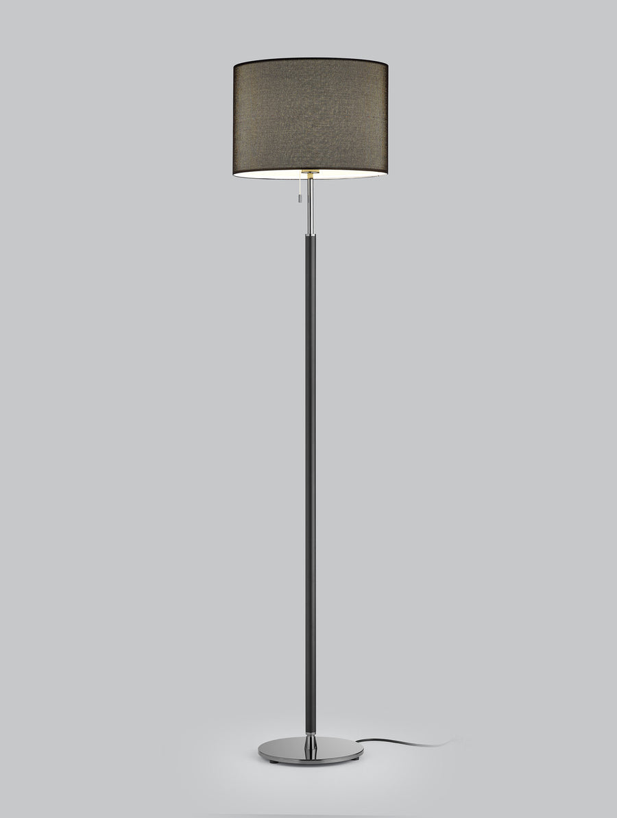 Lampadaire noir de face sur fond gris, abat-jour cylindrique et pied fin