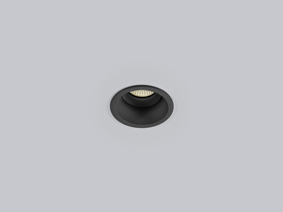 Spot encastrable noir vu de face, collerette ronde affleurant un plafond gris clair