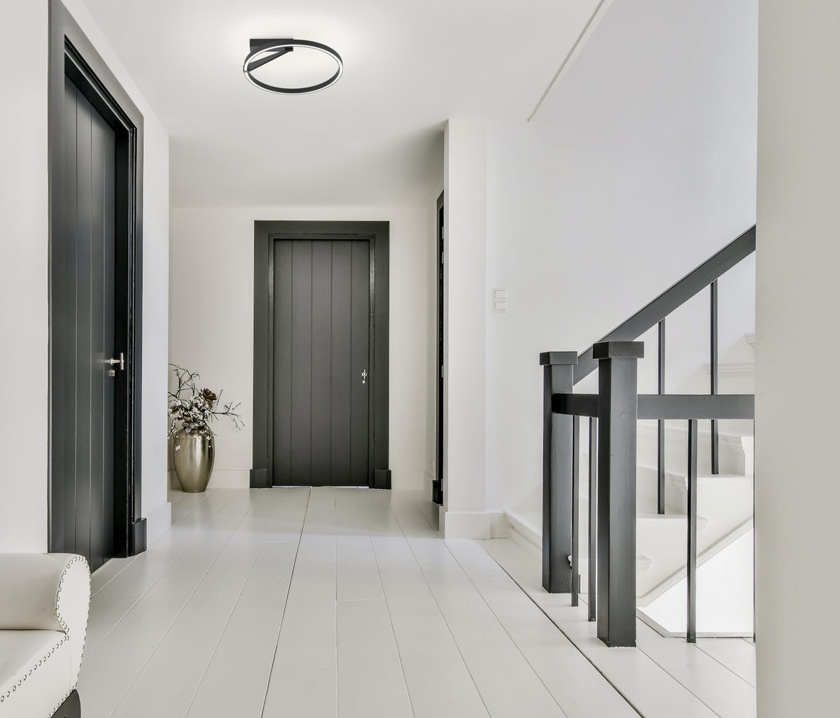 Mise en ambiance dans un couloir blanc, plafonnier noir allumé au plafond