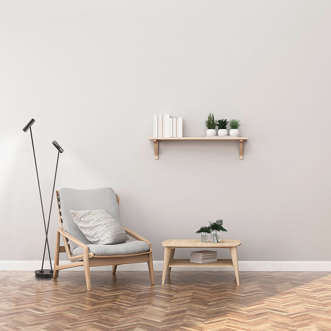 Mise en ambiance salon : lampadaire posé près d'un fauteuil en bois clair et étagère murale