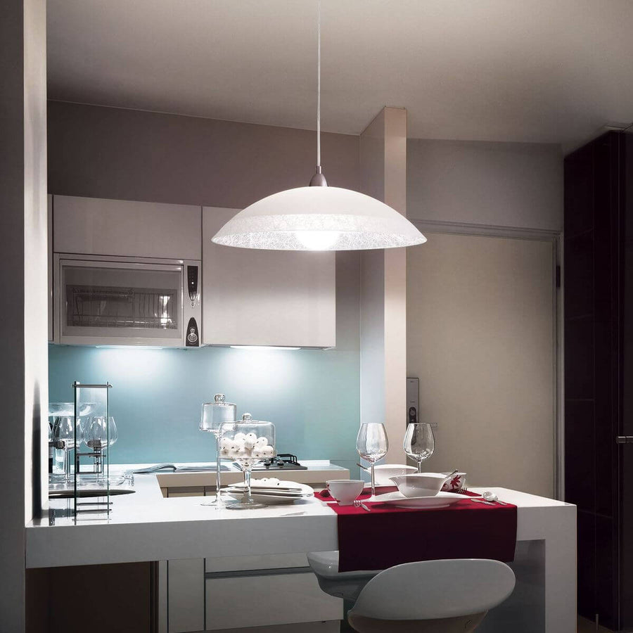 Suspension allumée au-dessus d'un îlot de cuisine moderne avec verres et assiettes