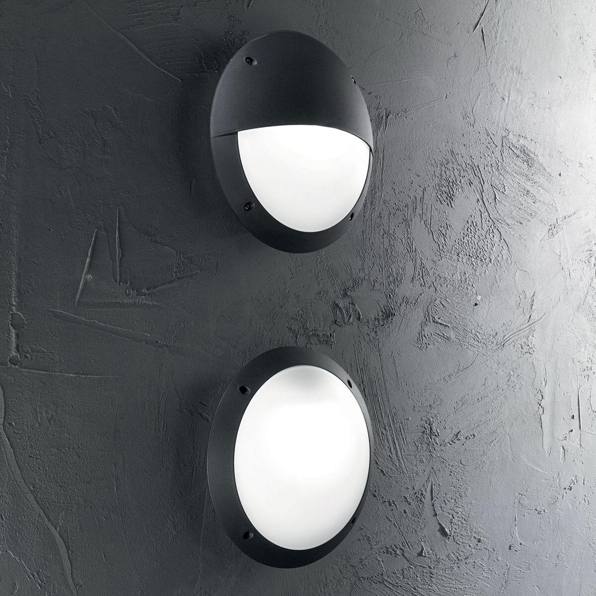 Deux appliques rondes noires installées sur un mur gris texturé, ambiance extérieure contemporaine