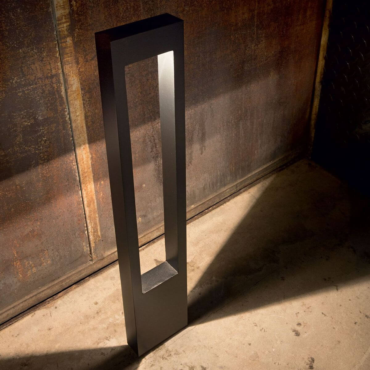 Mise en ambiance du lampadaire allumé contre un mur rouillé