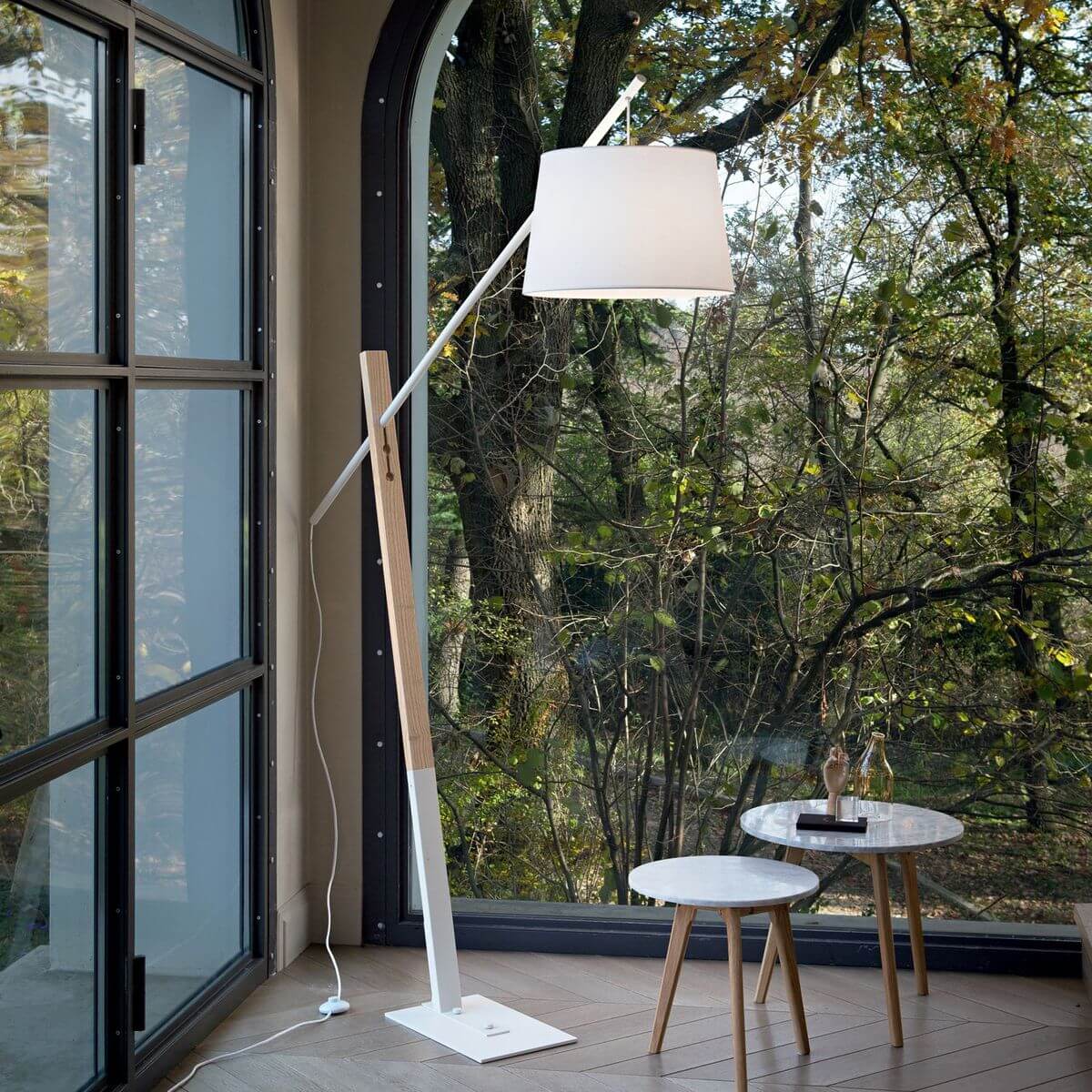 Mise en ambiance du lampadaire près d'une grande baie vitrée donnant sur des arbres