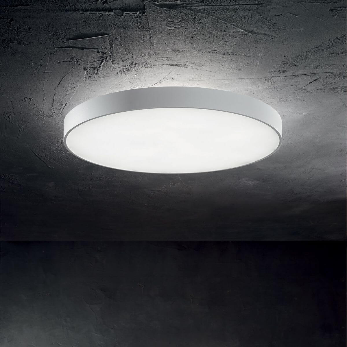 Luminaire allumé au plafond dans une ambiance sombre, mur béton texturé