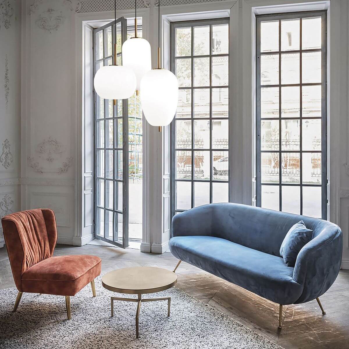 Mise en ambiance salon haussmannien, suspension allumée au-dessus d'une table basse ronde