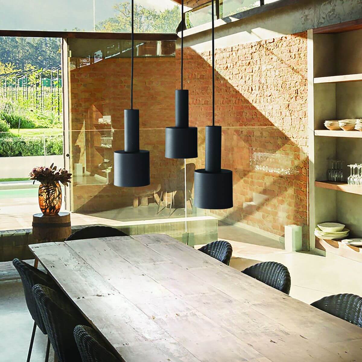Trois suspensions noires suspendues au-dessus d'une table en bois dans un intérieur.