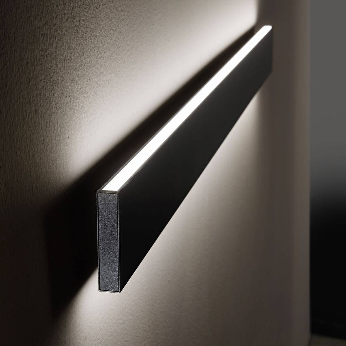 Vue en situation de l applique allumée projetant une lumière rasante sur le mur