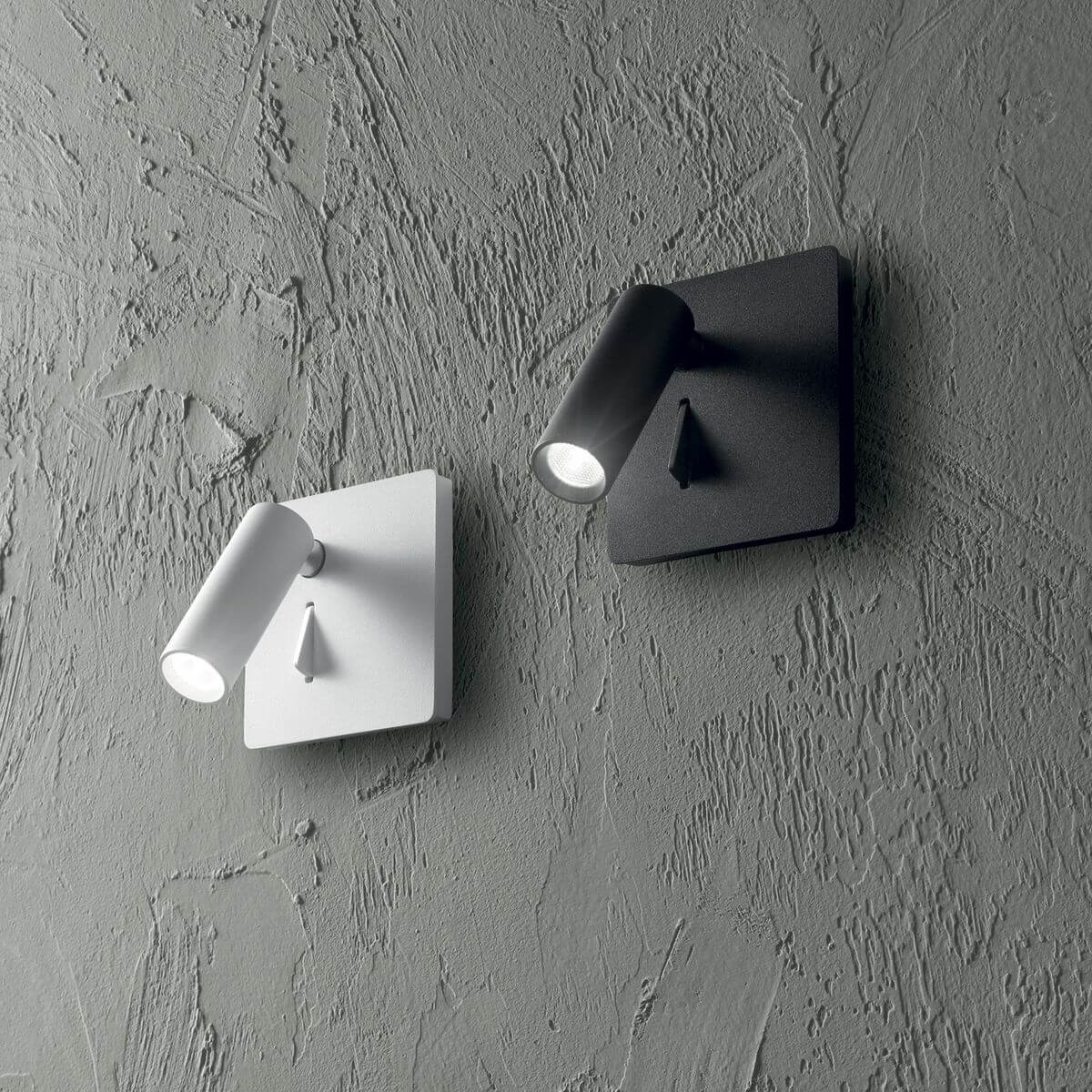 Deux appliques murales identiques, noire et blanche, posées sur mur gris texturé