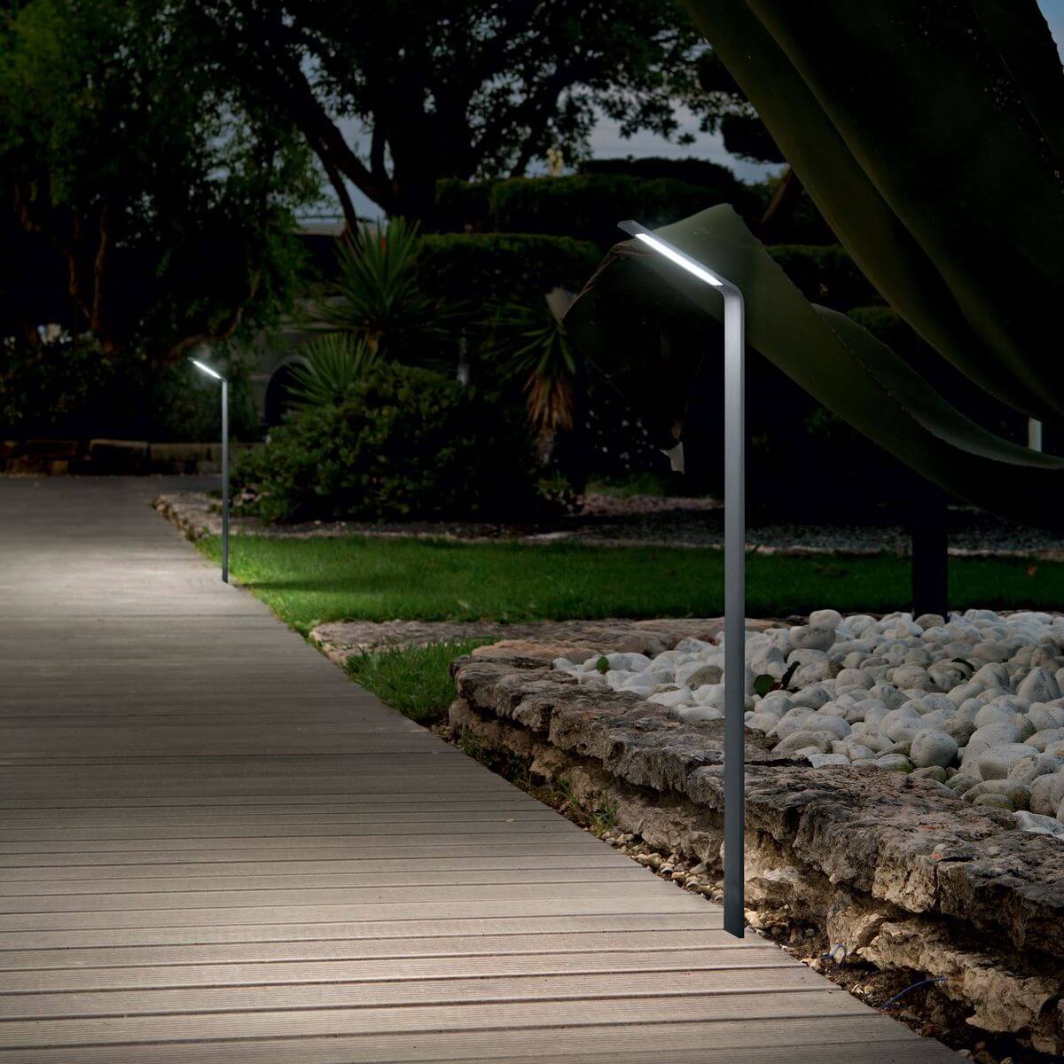 Mise en ambiance nocturne sur terrasse en bois bordée de galets, halo lumineux au sol