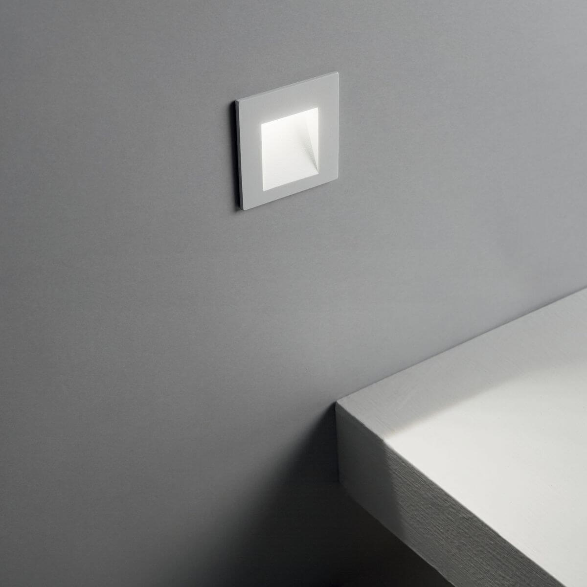 Spot encastré blanc allumé dans un mur gris, ambiance extérieure
