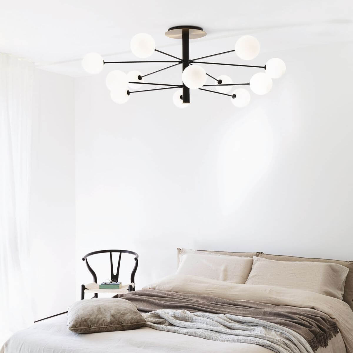 Mise en ambiance du plafonnier allumé au-dessus d'un lit dans une chambre claire.