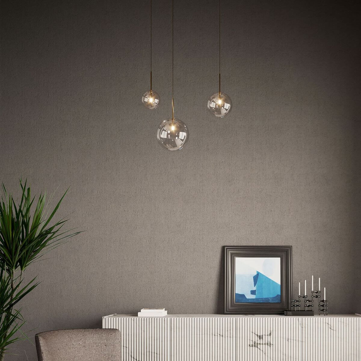 Trois suspensions boules en verre transparent suspendues devant un mur gris, décor minimaliste