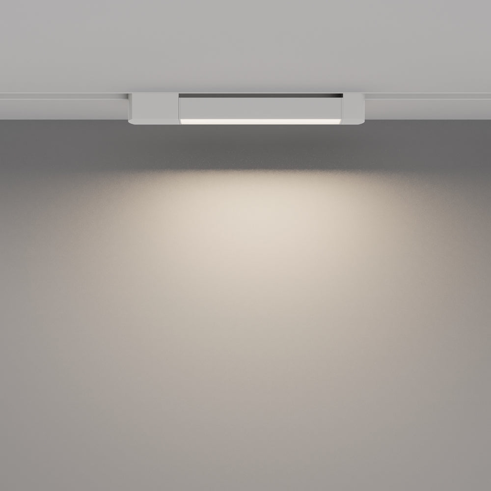 Luminaire allumé projetant un halo de lumière chaude sur le mur gris.