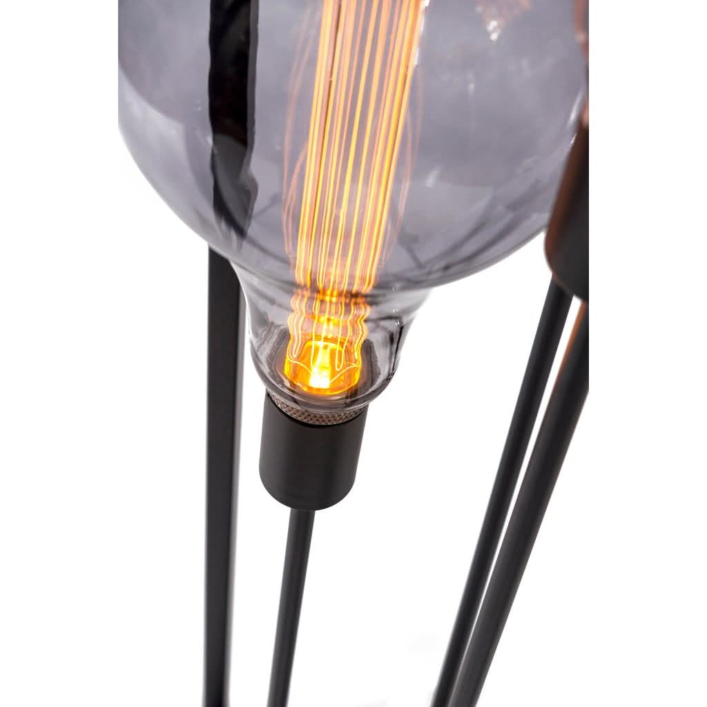 Très gros plan sur une ampoule à filament, douille noire et tiges métalliques du lampadaire.