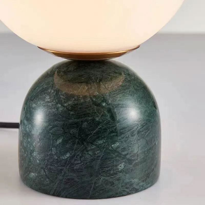Gros plan sur la base en marbre vert veiné et sa bague dorée