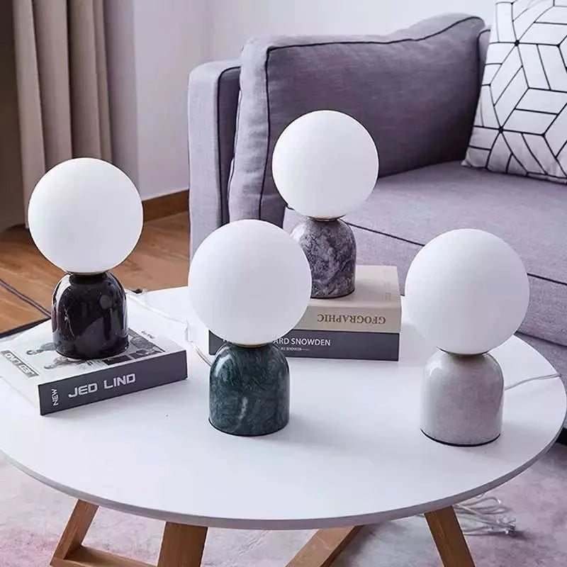 Quatre exemplaires aux bases marbre noir, vert, rose et gris sur table basse