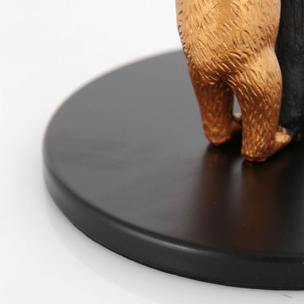 Détail des pattes arrière dorées sur la base ronde noire mate