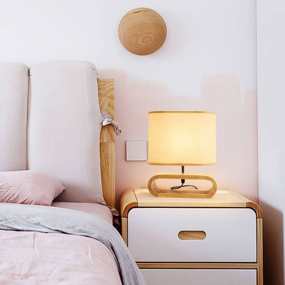 Lampe posée sur une table de nuit en bois dans une chambre rose pastel