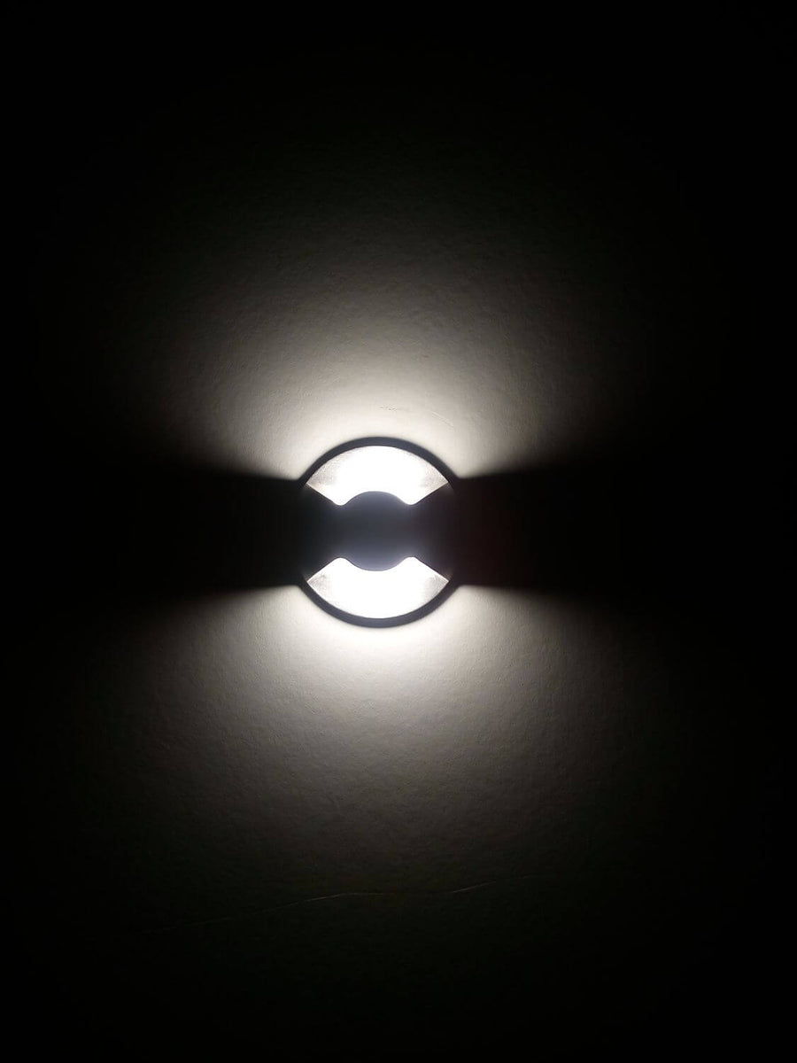 Luminaire encastré allumé dans l'obscurité, halo lumineux projeté sur une paroi sombre