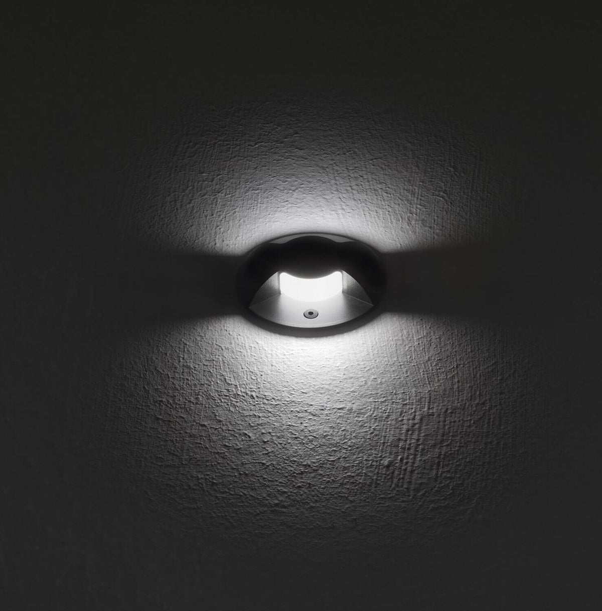 Mise en ambiance nocturne, faisceau blanc dirigé sur un mur gris texturé