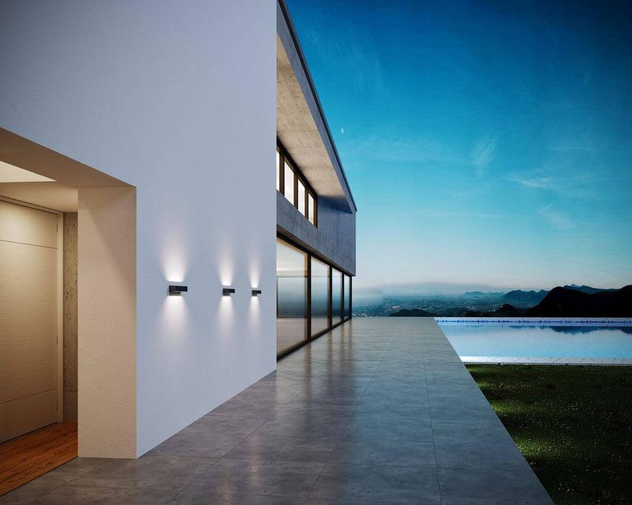 Façade moderne au crépuscule avec trois appliques et piscine en contrebas