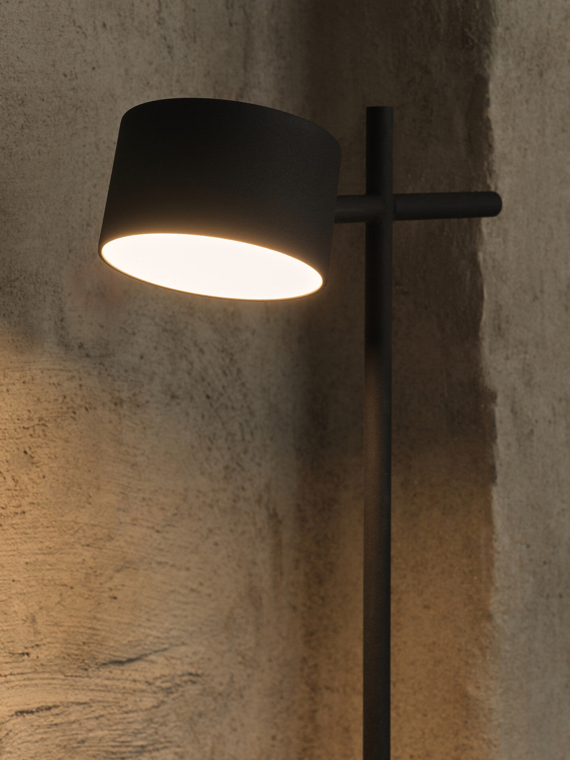Détail de l'abat-jour allumé projetant une lumière chaude sur le mur