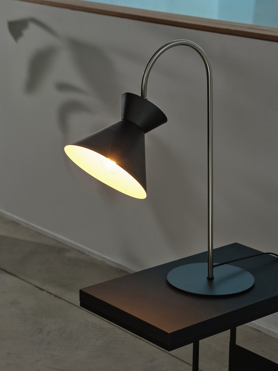 Lampe allumée projetant la forme de son abat-jour sur le mur en arrière-plan.