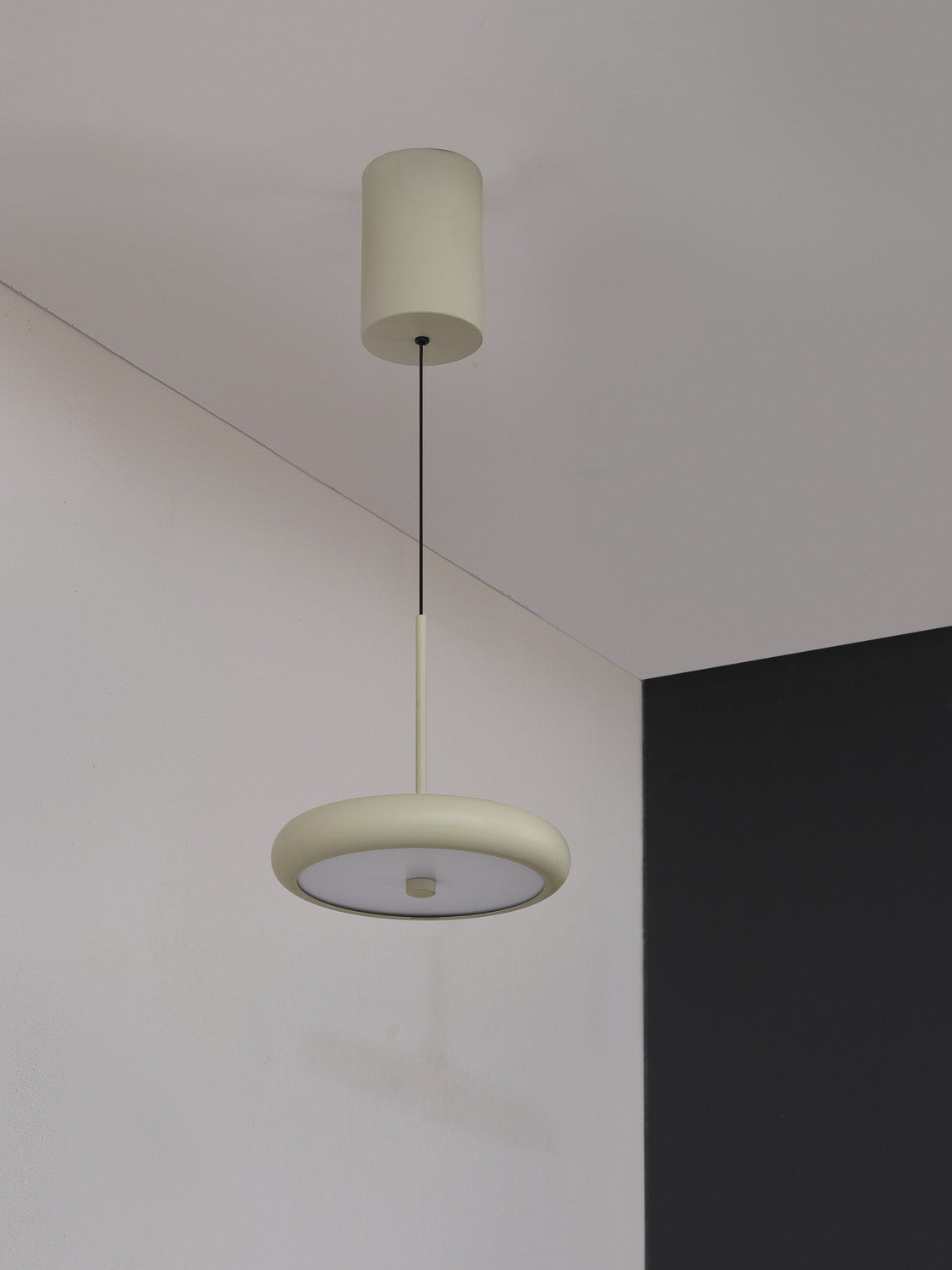 Suspension beige installée au plafond dans un angle de pièce claire.