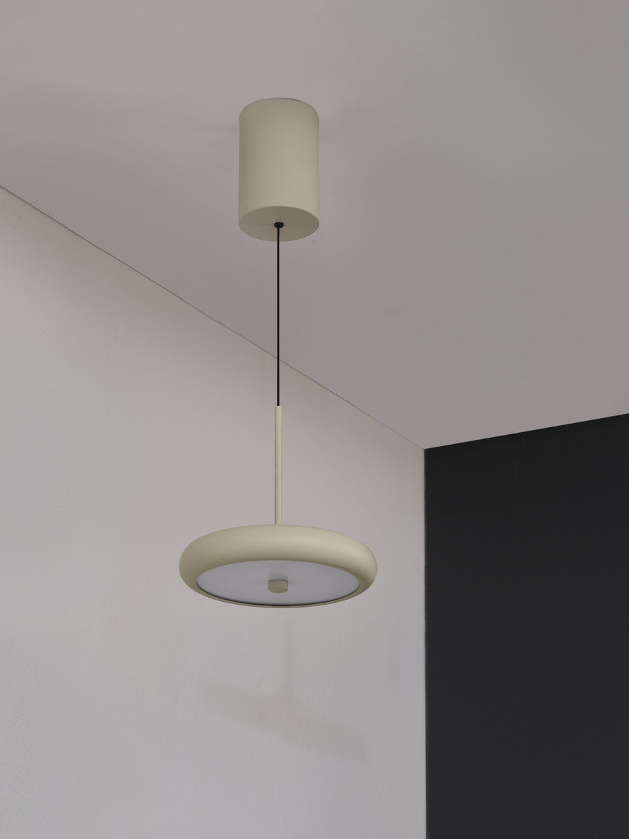 Suspension beige installée au plafond dans un angle de pièce claire.
