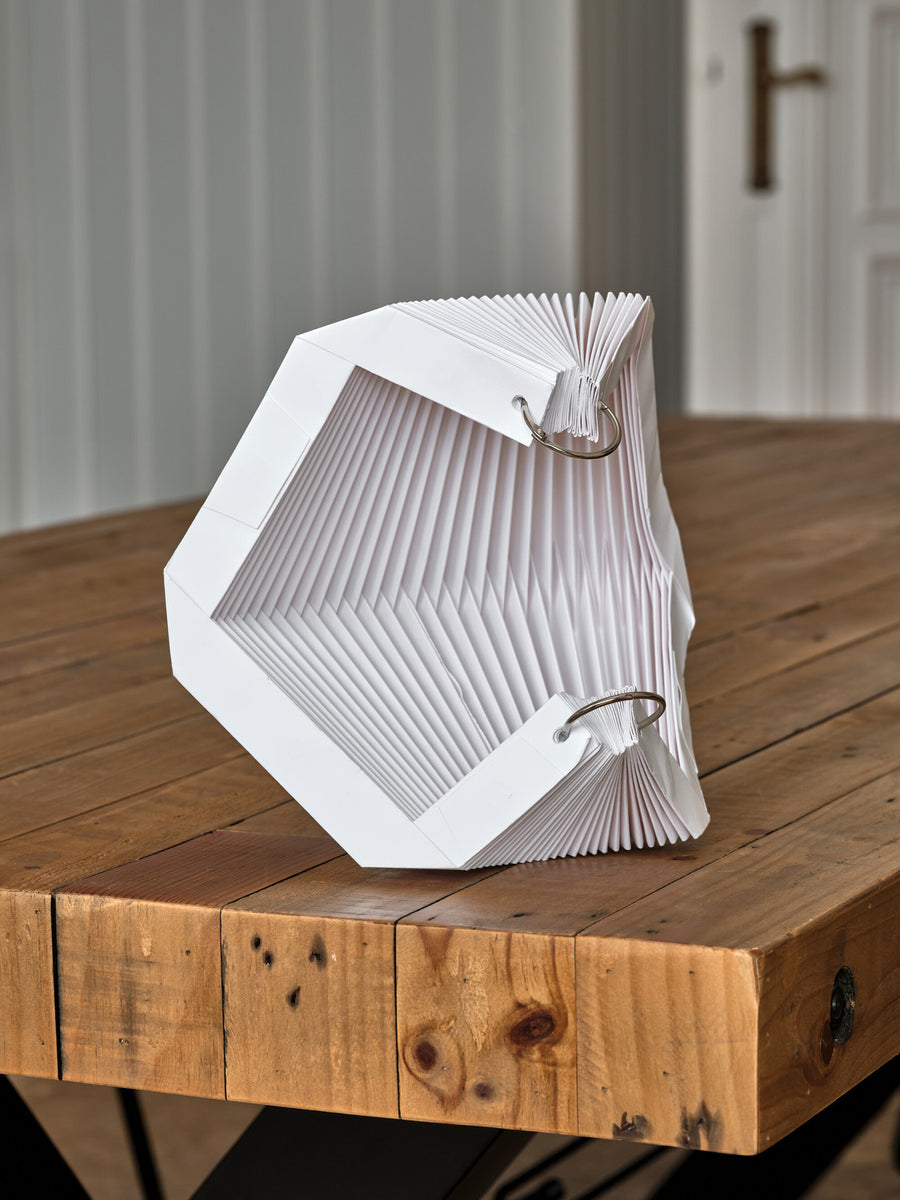 Abat-jour déplié posé sur une table en bois, vue intérieure.