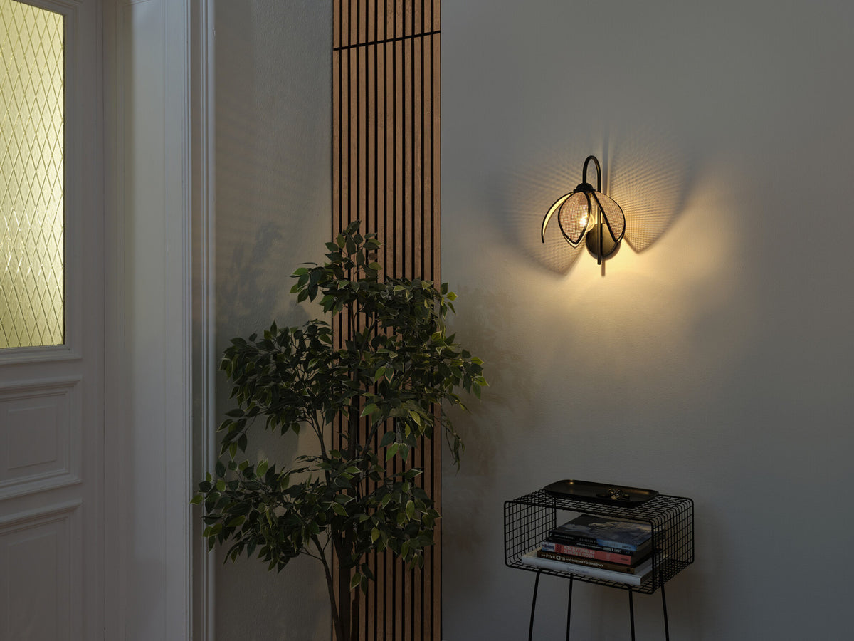 Mise en ambiance dans une entrée avec l'applique allumée, plante et meuble latéral.