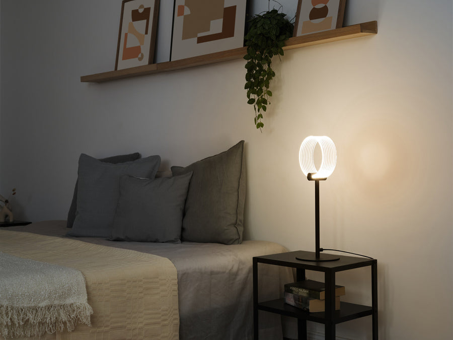 Lampe à poser diffusant une lumière chaude sur une table de chevet, scène de chambre.