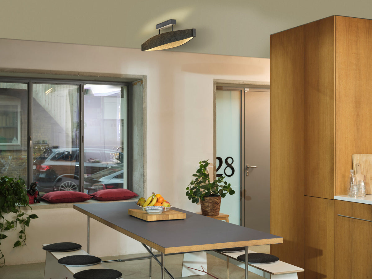 Mise en ambiance, le luminaire éclaire une table de salle à manger dans un intérieur moderne.