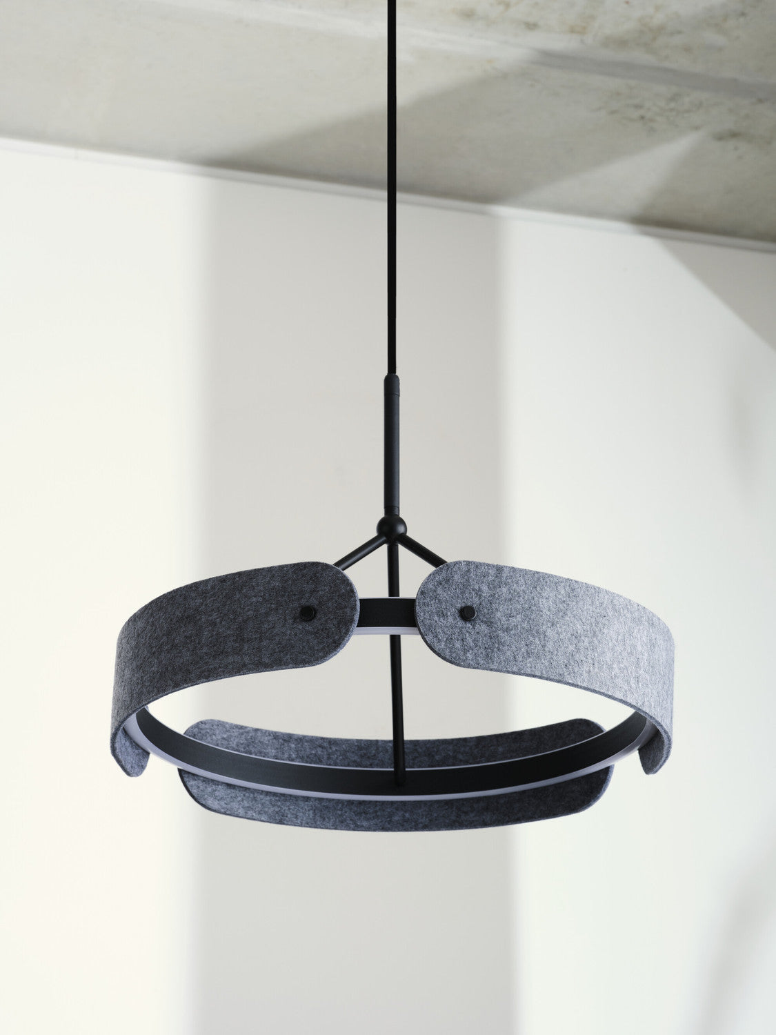 Détail rapproché des panneaux en feutre anthracite et de la structure noire.