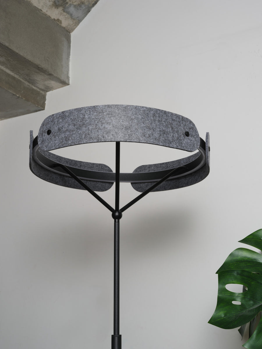 Détail de l'abat-jour en feutre gris et de la structure métallique noire.