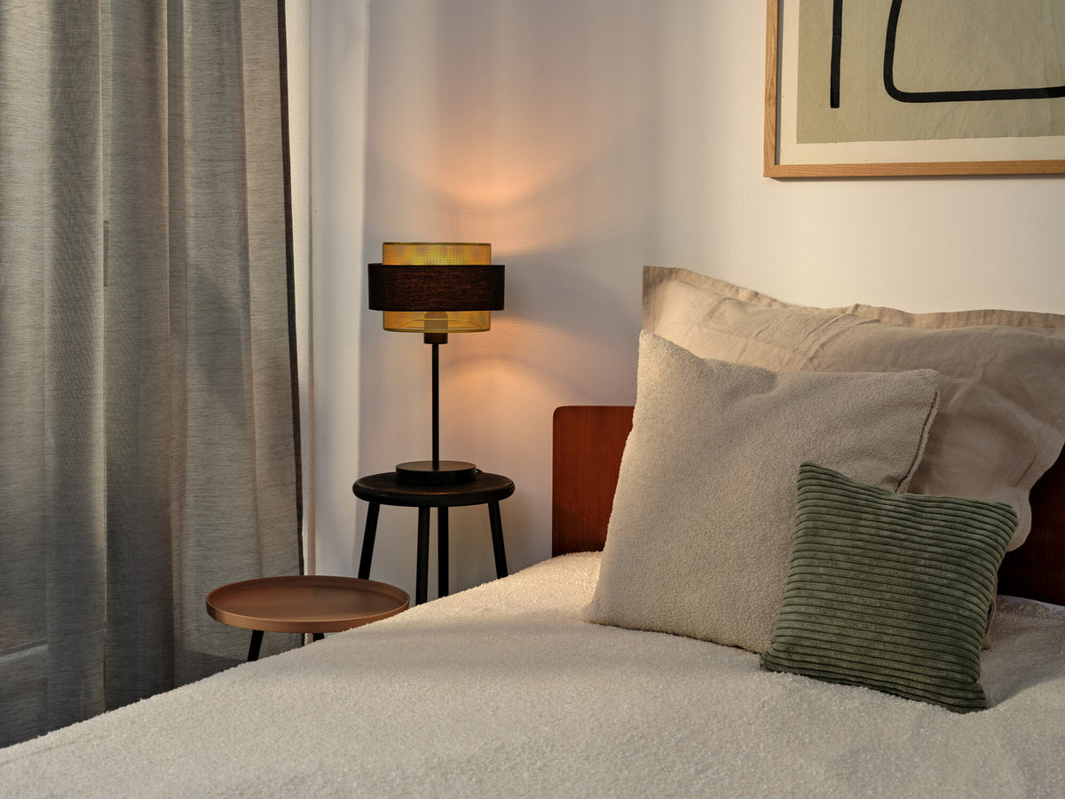 Lampe à poser allumée sur une table de chevet dans une chambre