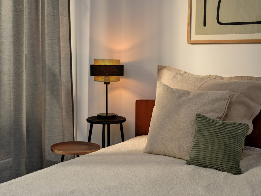 Lampe à poser allumée sur une table de chevet dans une chambre