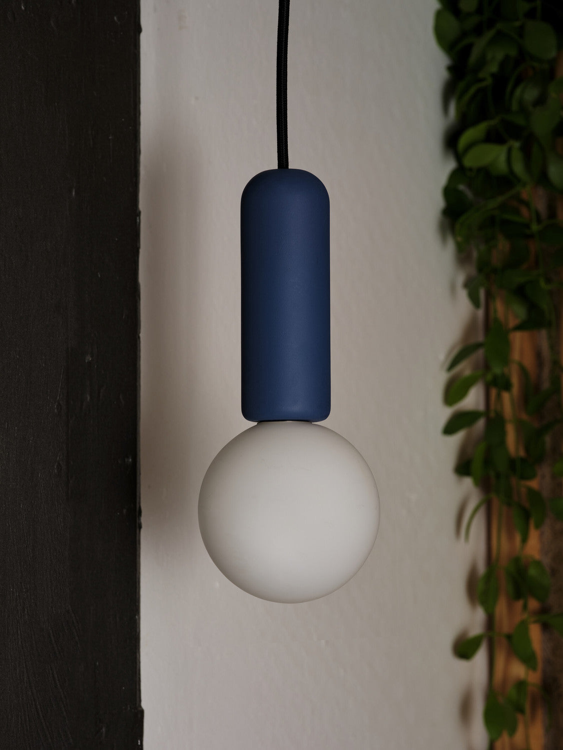 Gros plan de la suspension bleue éteinte devant un mur blanc
