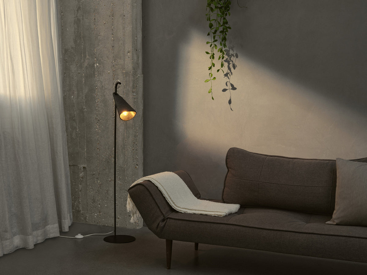 Scène d'ambiance montrant le lampadaire éclairant un salon aux tons gris.