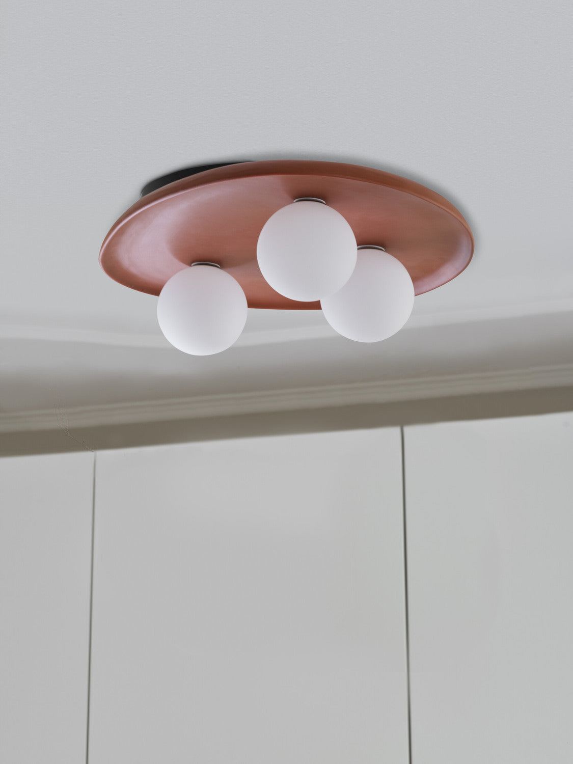 Vue rapprochée du luminaire fixé au plafond, trois sphères blanches