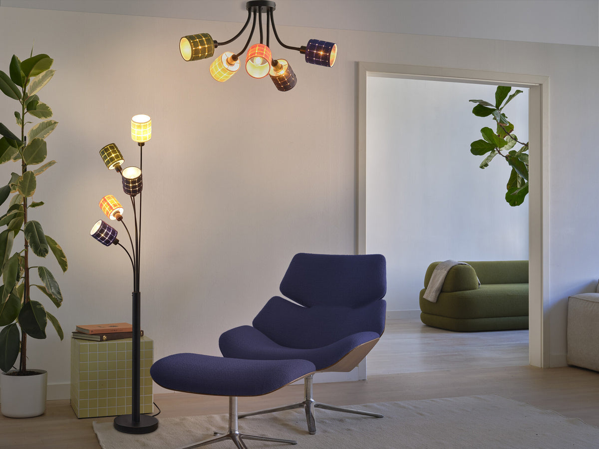 Scène de salon avec le plafonnier fixé au plafond et allumé au-dessus du fauteuil bleu.