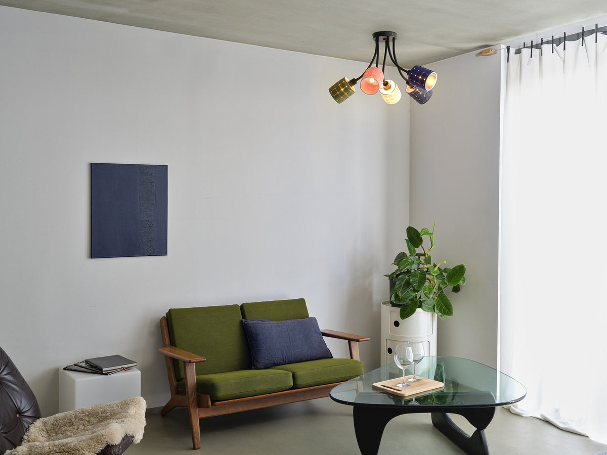 Vue d’ensemble d’un salon avec le plafonnier multicolore allumé au-dessus de la table basse.