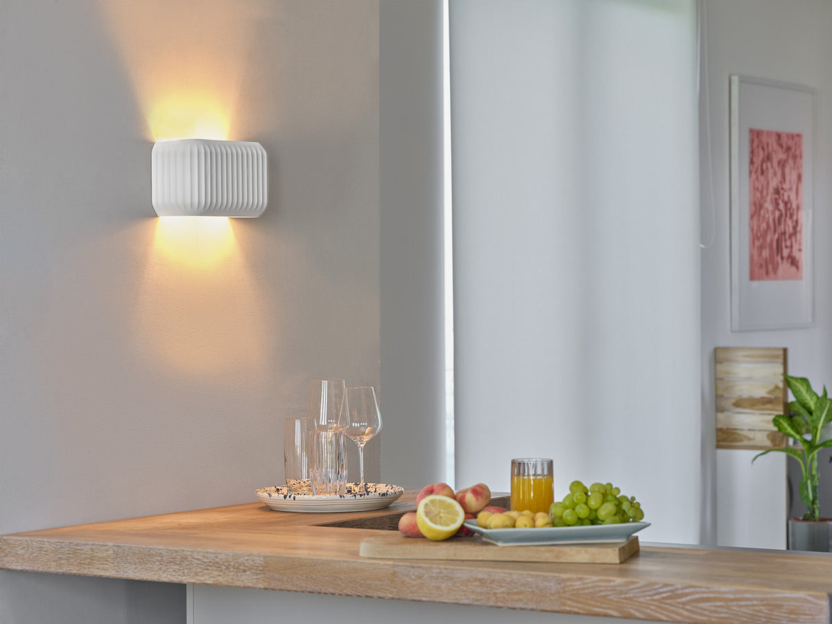Mise en ambiance au-dessus d’un plan de travail en bois, éclairant le mur et des fruits.