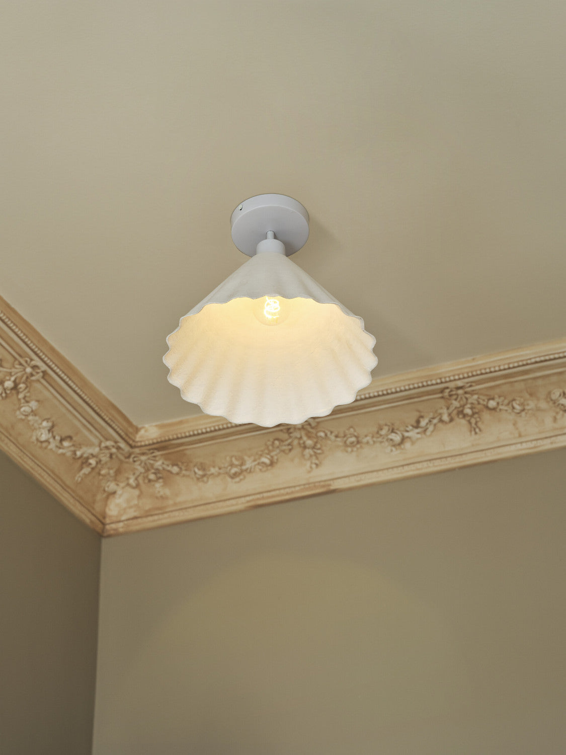 Vue en contre-plongée du plafonnier allumé près d'une moulure décorative.