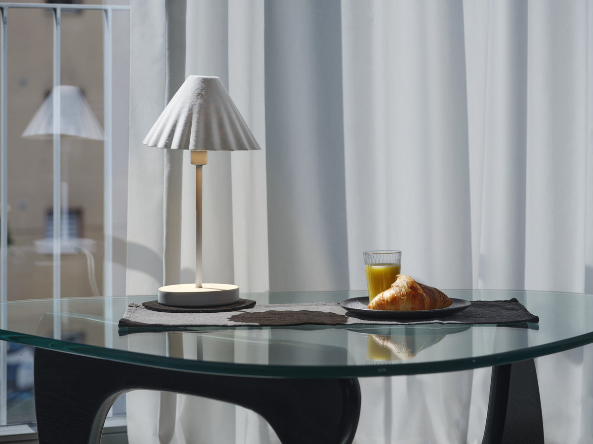 Mise en ambiance sur table en verre au petit-déjeuner, lumière allumée près d'un croissant.