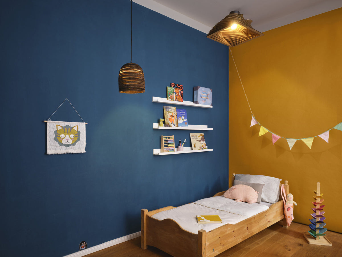 Vue d'ensemble d'une chambre bleue et moutarde avec la suspension allumée.