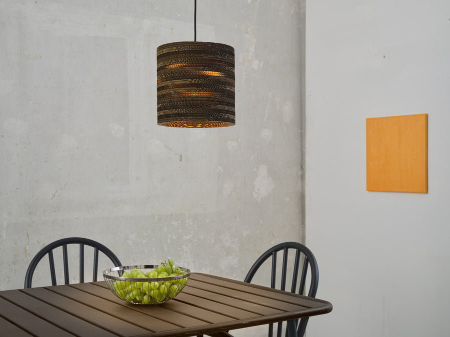 Suspension en carton allumée au-dessus d'une table en bois avec une corbeille de raisins.